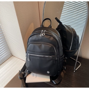 Close-up of black pebble grain backpack featuring silver hardware and multi-pocket design