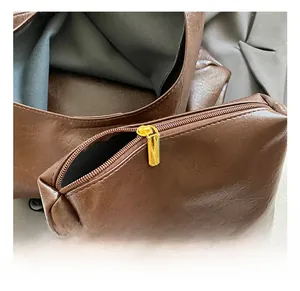 Détail du sac fourre-tout en cuir marron grainé avec une pochette dorée zippée