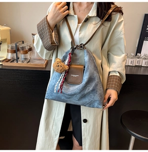 Détail du sac cabas en denim bleu clair avec rabat en cuir marron et breloque ourson