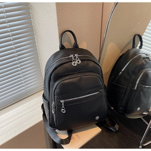 Detail of black lychee texture backpack featuring multi-zipper layers and metal logo