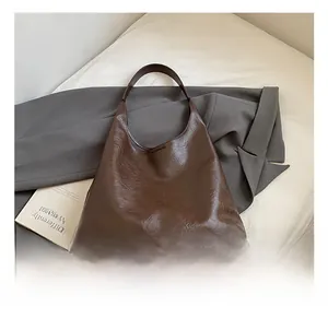 Détail du sac cabas en cuir marron foncé avec texture naturelle sur fond minimaliste