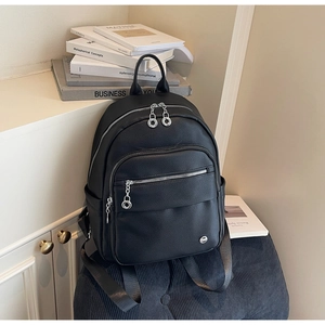 Close-up of black lychee texture leather backpack with silver zippers and metal charms