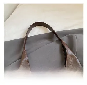 Gros plan détaillé de la poignée en cuir avec double couture d'un cabas marron
