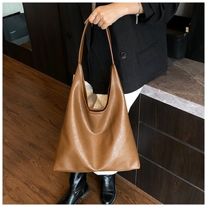 Gros plan détaillé sur la texture grainée du grand sac cabas marron en cuir pour le bureau