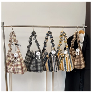 Détail de sacs hobo en peluche à carreaux avec anses froncées et breloque poupée