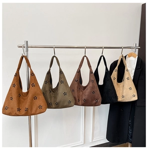 Detail of five hollow-out suede tote bags in various colors with laser-cut floral patterns
