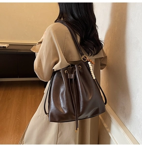 Detail view of deep brown drawstring bucket bag with decorative beads and double straps