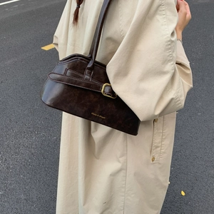 Detail van een donkerbruine vintage schoudertas op een beige trenchcoat voor dames
