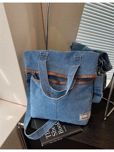 Denim tote bag with brown leather trim and wide adjustable shoulder strap for women