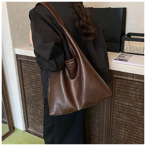 Détail du grand sac cabas vintage marron foncé avec cuir texturé porté à l'épaule de femme