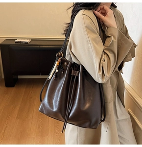 Detail of dark brown bucket bag with ethnic beaded tassel and drawstring closure