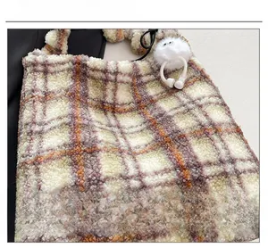 Gros plan du sac cabas à carreaux en peluche avec tissu violet et pendentif monstre