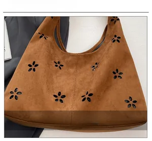 Detail view of the brown faux suede tote bag with decorative floral hollow cut-outs