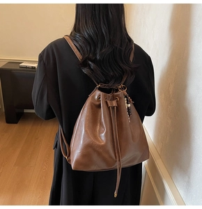 Detail of a brown bucket backpack with drawstring closure and decorative beads