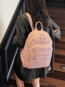 Pink lychee grain faux leather backpack with double metal zippers on modern stairs background