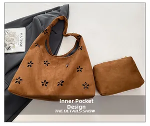 Detail of brown suede tote bag featuring laser-cut floral patterns and an inner pouch
