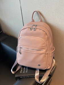 Pink lychee grain leather backpack with spacious pockets on a stylish black leather bench