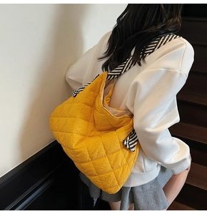 Detail of quilted yellow tote bag with distinctive black and white striped shoulder strap