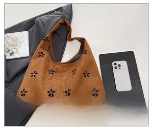 Detail showing laser-cut floral pattern on brown suede leather shoulder tote bag