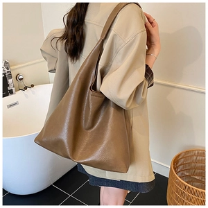 Grand sac fourre-tout marron porté avec un trench beige pour un look de bureau