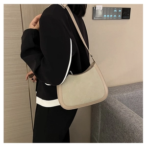 Détail du sac hobo beige montrant les coutures en cuir et le logo doré embossé