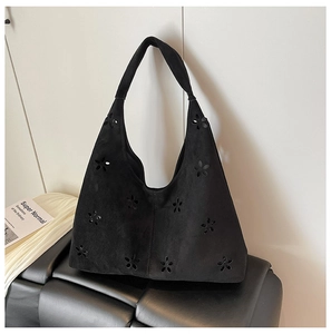 Detail of laser-cut flower pattern on black suede shoulder bag with a vintage design