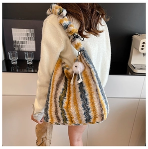 Détail d'un sac cabas en peluche à rayures colorées avec texture douce et pompon blanc