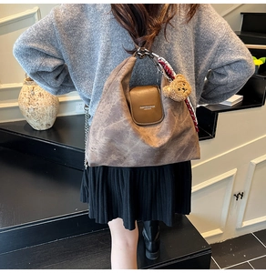 Détail d'un sac cabas marron vintage avec rabat en cuir, foulard en soie et breloque ours