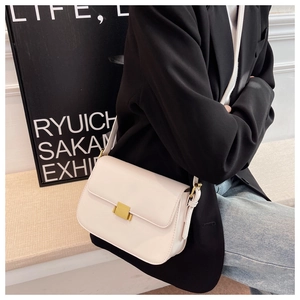 Side view of an elegant off-white crossbody bag with golden square clasp on a model