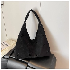 Detail shot of black suede hobo tote featuring laser-cut floral patterns and wide strap