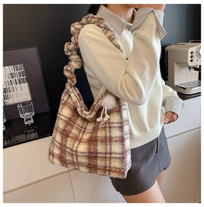 Détail du sac cabas en peluche à carreaux avec bandoulière à volants et pompon blanc