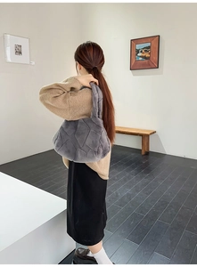 Rear view of a model carrying the large grey faux fur tote bag with quilted diamond pattern