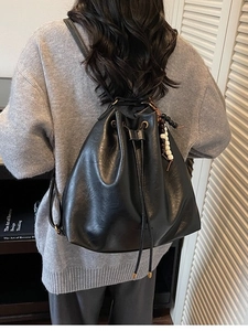 Minimalist black PU leather bucket backpack with drawstring and beaded charm detail