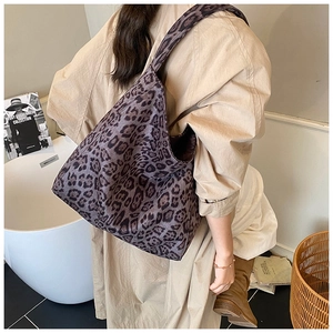 Detail of purple leopard print tote bag with wide shoulder strap worn by a model