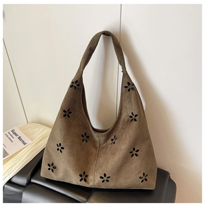 Detailed view of dark brown suede tote bag featuring artistic hollow-out floral patterns