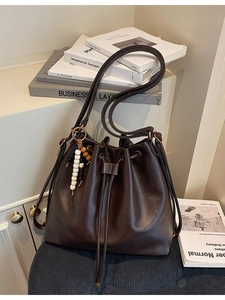 Dark brown pleated leather bucket bag with drawstring closure and beaded charm tassel