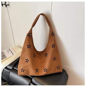 Detail of laser-cut floral hollow pattern on brown suede tote bag texture
