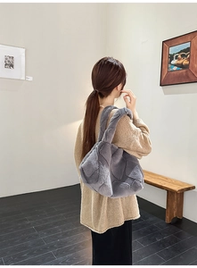 Detailed view of grey faux fur tote bag with textured surface styled on shoulder