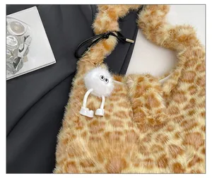 Detail of plush leopard print tote bag featuring a cute fuzzy monster pendant charm