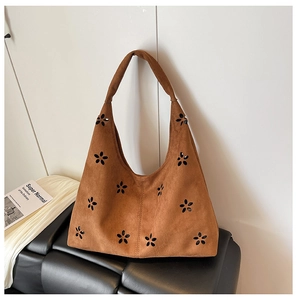 Detail of brown suede tote bag with floral cut-out patterns on a minimalist background