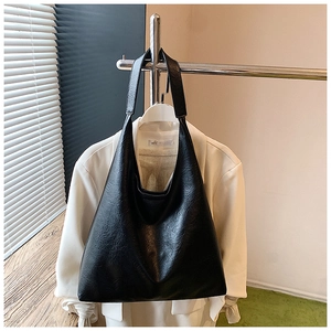 Détail du sac hobo noir minimaliste en cuir texturé avec une simple bandoulière