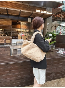 Detail of a large beige faux fur tote bag with circular quilted pattern and metal hardware