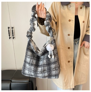 Détail d'un sac cabas en peluche à carreaux gris et blanc avec un pompon décoratif