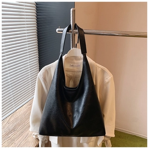 Détail d'un grand sac cabas noir suspendu à un support à côté d'un blazer blanc chic