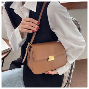 Close-up of caramel leather crossbody bag featuring a classic gold metal buckle and flap