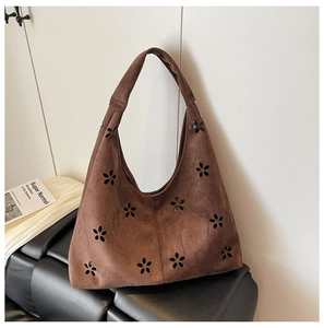 Detail of laser-cut floral patterns on dark brown faux suede tote bag for women