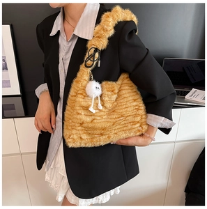 Detail of striped faux fur tote bag featuring a quirky white plush monster keychain charm