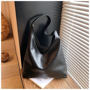 Gros plan sur un sac cabas minimaliste en cuir noir mat avec une texture froissée
