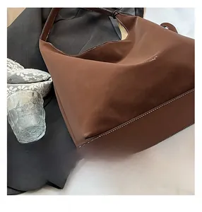 Detail of brown tote bag featuring white contrast stitching and minimalist matte leather texture