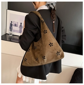 Detail of laser-cut floral pattern on brown suede tote bag with matte texture finish